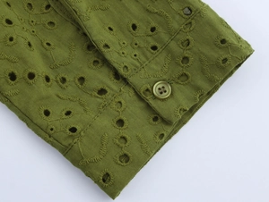 Detailed macro view of olive green cotton shirt cuff with delicate eyelet embroidery