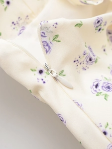 Gros plan sur la fermeture éclair invisible de la robe ivoire à fleurs violettes