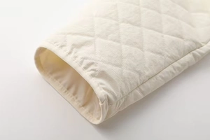 Detailed close-up of cream quilted jacket sleeve with fine diamond stitching pattern