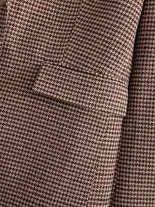 Detailaufnahme des Hahnentritt-Blazers mit gewebter Textur, Tasche und bernsteinfarbenem Knopf