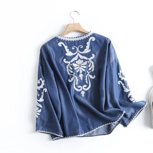 Detailed white flower embroidery on the back of a vintage blue denim long-sleeve blouse