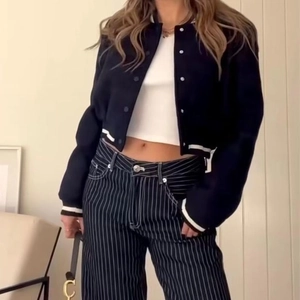 Women's Y2K style black cropped bomber jacket with white striped ribbing and snap buttons