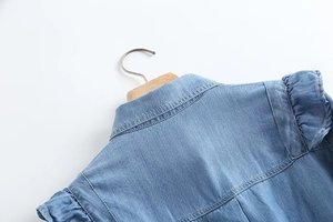 Detailed view of ruffle stitching and denim texture on the back of light blue shirt
