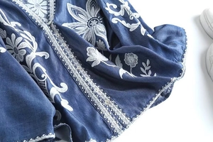 Detailed close-up of blue floral embroidery and white lace on the vintage denim shirt