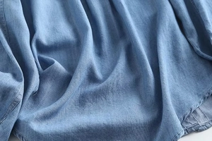 Close-up of light blue denim fabric showing fine twill texture and soft drape detail