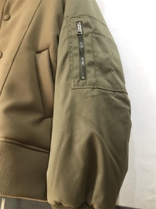 Detail der Bomberjacke mit khakifarbenem Rumpf und olivgrünem Ärmel mit Reißverschlusstasche