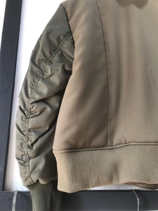 Detail der Bomberjacke in Armeegrün mit gerafften Ärmeln und gemischten Stoffstrukturen