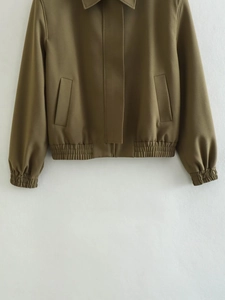 Detail of olive green utility jacket featuring hidden zipper and elastic waistband