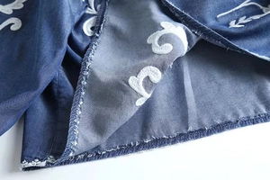 Detailed macro view of white embroidery on premium blue denim fabric with neat stitching