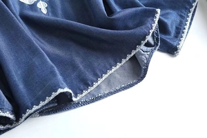 Detailed shot of white floral embroidery on blue denim fabric of a vintage shirt