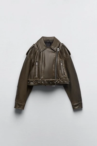 Detailed macro view of cropped moto jacket showing faux leather texture and belt