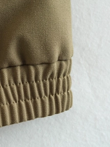 Detailed close-up of elastic ribbed cuff on khaki cargo jacket with high quality stitching
