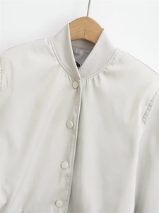 Detail of light grey bomber jacket featuring ribbed collar and metallic snap buttons