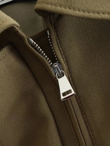 Detailed macro view of the silver metal zipper and durable twill fabric on a cargo jacket