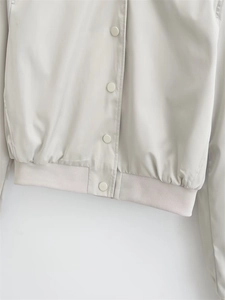 Close-up of Y2K pilot jacket snap buttons and elastic ribbed hem detail in light grey