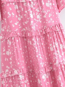 Gros plan d'une robe fleurie rose vif avec plusieurs couches de volants et motifs blancs