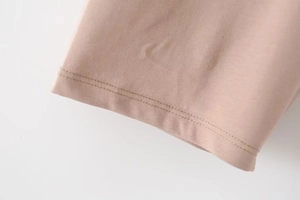 Macro shot of double-needle stitching on light brown knit t-shirt sleeve cuff detail
