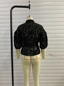 Detail eines schwarzen Puffärmel-Spitzentops mit filigranen Mustern und Taillenband