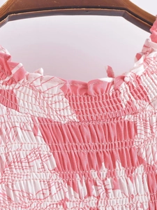 Detail of pink floral dress featuring smocked neckline and ruffled elastic collar