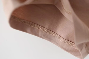 Macro shot of precise stitching on skin-toned fabric for stretch two-piece set