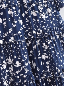 Détail du tissu bleu marine à fleurs avec des couches de volants et des petits motifs blancs