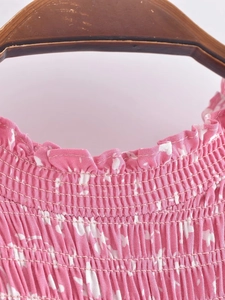 Détail du col à volants et du smock élastique sur la robe rose à fleurs