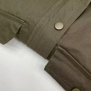 Close-up of military green canvas jacket with metal snap button and pocket detail
