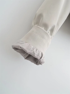 Macro detail of elastic ribbed cuffs and smooth woven fabric on Y2K bomber jacket