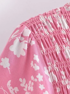 Détail du motif floral rose avec smocks et coutures précises sur une robe d'été