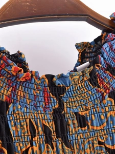 Detailed view of smocking texture and ethnic floral print on summer dress bodice