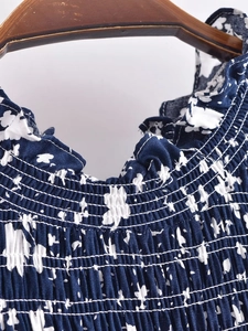 Détail du col smocké avec volants sur une robe bleu marine à fleurs en viscose