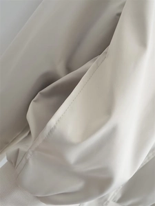 Detail of side pocket stitching and ribbed cuffs on light gray Y2K bomber jacket