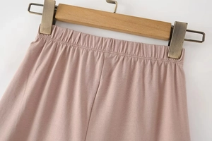 Detail view of pink knit leggings with elastic waistband on a wooden hanger