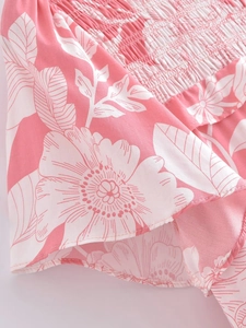 Detail of floral print dress with elastic smocking and pink flower pattern texture