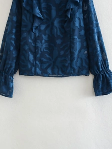 Detailed view of dark blue jacquard shirt with floral texture and ruffled collar details