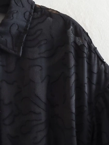 Detail des schwarzen Jacquard-Stoffs mit semitransparenter Textur und Puffärmeln