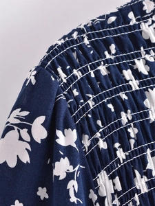 Détail macro du smock floral bleu marine et du tissu plissé avec surpiqûres blanches