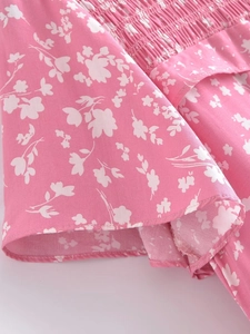 Détail d'une robe fleurie rose avec smocks élastiques et coutures précises sur l'ourlet