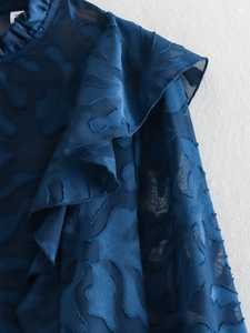 Detail of navy blue jacquard blouse with layered ruffles and stand collar texture