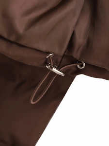 Macro detail of dark brown winter jacket featuring metallic drawstring toggle and elastic cord