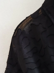 Nahaufnahme von schwarzem Jacquard-Stoff mit floraler Textur und Puffärmel-Detail