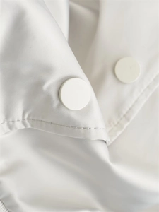 Detail of white Y2K flight jacket showing smooth fabric texture and round snap buttons