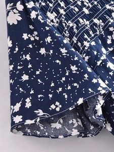 Détail de la couture smockée et imprimé floral blanc sur tissu viscose bleu marine