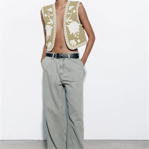 Green vintage vest with floral embroidery paired with wide-leg jeans and leather belt