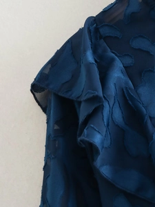 Macro shot of navy blue fil-coupé fabric featuring embossed leaf patterns and sheer textures