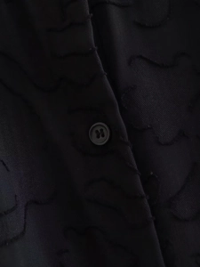 Detailansicht aus schwarzem Jacquard-Stoff mit Satinglanz und passendem Vierloch-Knopfverschluss