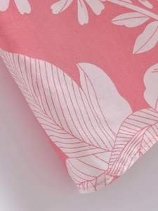 Detailed view of pink floral print fabric with white tropical leaves and neat stitching