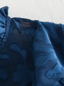 Detail of navy blue blouse showing 3D fil coupé jacquard texture and ruffled edges