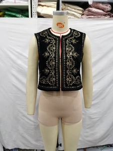 Detailed close-up of golden floral embroidery and sequins on black velvet vest