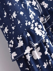 Détail d'une robe fleurie bleu foncé montrant les volants et la qualité de la couture